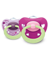 Purple background with pink hearts on it, featuring two NUK soothers which are purple and pink with glow in the dark handles.